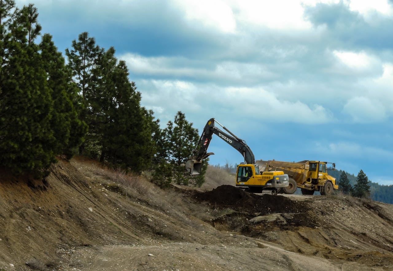 Excavator and truck working at a construction site in Coeur dAlene, Idaho with cloudy skies.